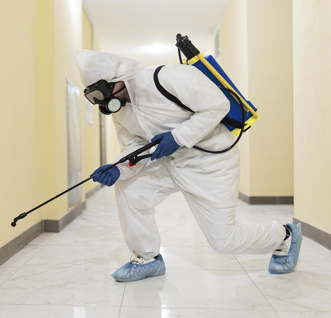 Full shot man disinfecting building